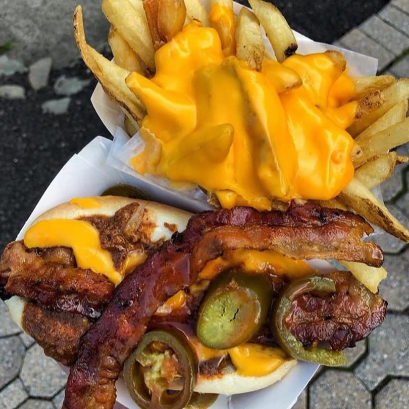 A chili cheese dog with bacon and jalapeños, next to a container of cheese fries from Jersey Johnny's Grill.